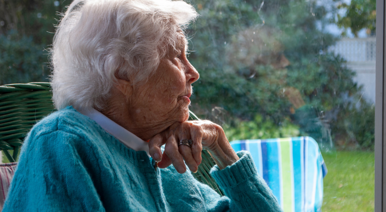 Side View of a elderly person looking out a window