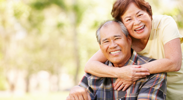 Elderly Couple Hugging while looking at viewer